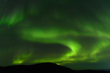 Aurora borealis over the hills. At night in the sky in the north.