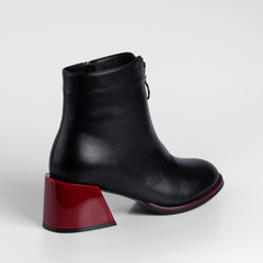 Graceful black womens leather demi season ankle boots in low fat red heels. Studio photo for catalog