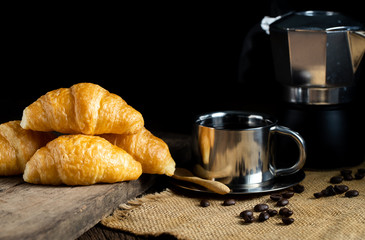 Coffee and croissants on the wooden background, top view