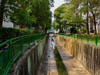 Fototapeta na wymiar Tree lined water canal channel in a residential housing estate in Singapore