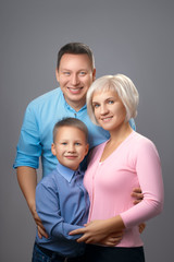 Vertical portrait of a beautiful smiling European family against a gray background in the studio