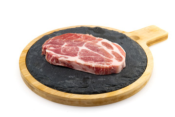 raw pork steak on black stone and wood. Pork with spices: rosemary and pepper. Close-up raw pork steaks.