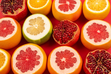 Grapefruit, orange, pomegranate, citrus sweetie on red background.