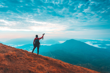 Silhouette of man hold up hands on the peak of mountain