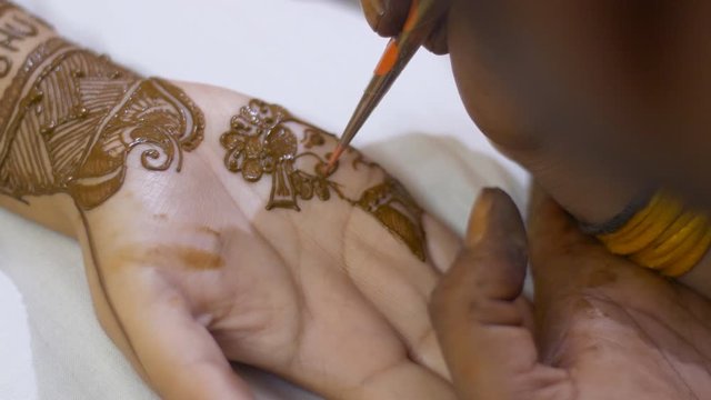 Mehndi artist applying beautiful henna / mehndi of the hands of an Indian bride. Indian Mehndi artist applying henna - Indian wedding ritual in a traditional family. Festival preparation ritual 