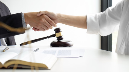 Lawyer and client handshake with contract agreement signing in law firm.