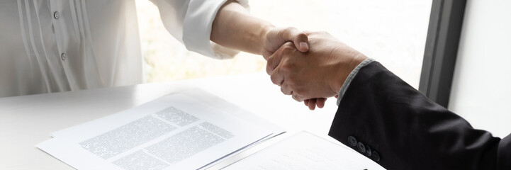 Lawyer and client handshake with contract agreement signing in law firm.