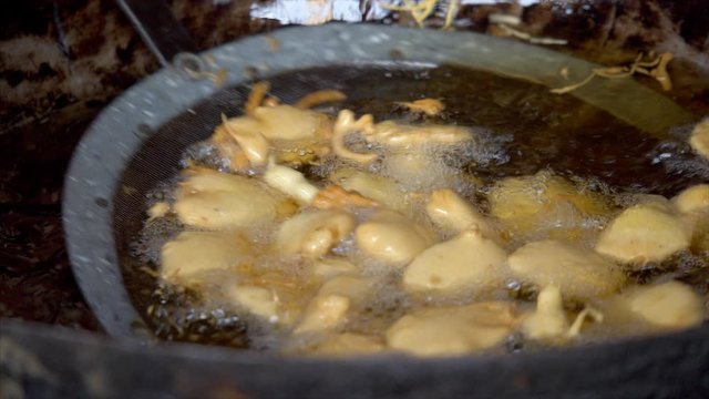 Closeup shot of pakoras (fritters) being prepared in hot oil for guests at the Indian wedding. Indian chef cooking aloo pakoras at the marriage ceremony  also known as pakode  pakoda  bhajia - frie...