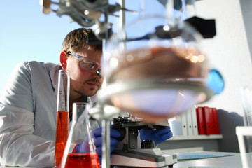 Portrait of a young chemist looking in binocular