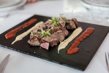 rinderfilet kurzgebraten und angerichtet auf einer Schiefertafel mit Mayo und Salsa