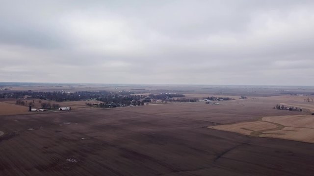 Aerial fly over view of harvested fields and timber woods during a cloudy day