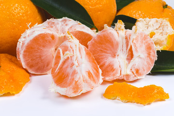 Peeled tangerine divided into segments against the other tangerines