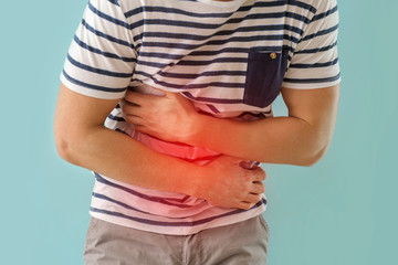 Young man suffering from abdominal pain on color background