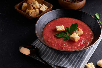 Homemade Spanish tomato soup Gazpacho with spice in black bowl on dark stone background