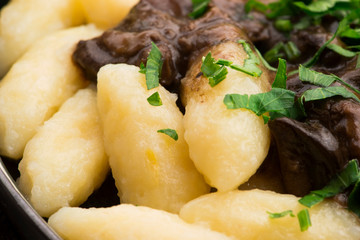 Freshly cooked, Polish traditional potato dumplings serving with mushroom sauce and fresh parsley