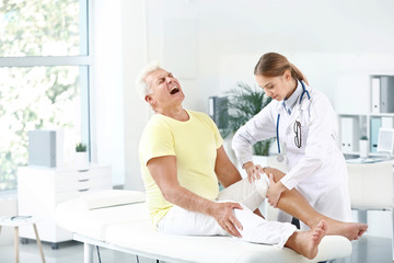 Obraz premium Doctor examining mature man with joint pain in clinic