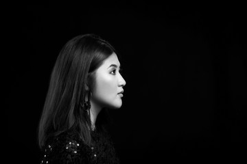 Black and white portrait of young Asian woman on dark background