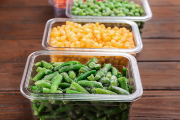 Different tasty frozen vegetables on wooden table