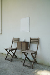 흰 벽에 블랭크 배너 그리고 나무 소재로 된 의자와 작은 테이블이 어울린 모습입니다.