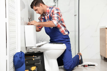 Professional plumber working with toilet bowl in bathroom - obrazy, fototapety, plakaty