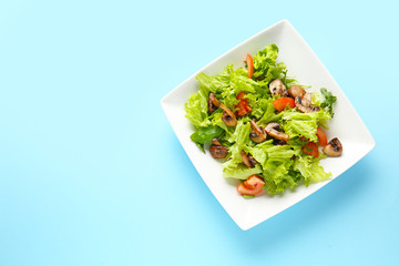 Plate with tasty mushroom salad on color background