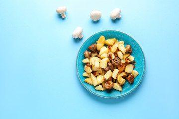 Plate with tasty cooked mushrooms and potato on color background