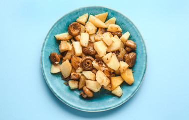 Plate with tasty cooked mushrooms and potato on color background