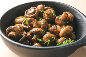 Frying pan with tasty cooked mushrooms on light background, closeup
