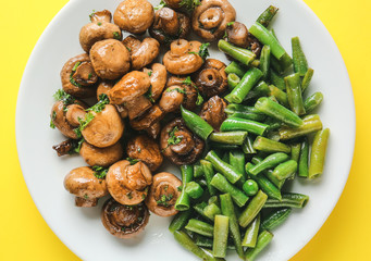 Plate with tasty cooked mushrooms and green beans on color background