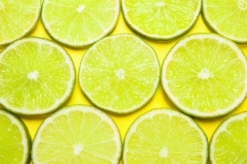 Fototapeta na wymiar Juicy fresh lime slices on yellow background, flat lay
