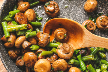 Frying pan with tasty cooked mushrooms and green beans, closeup