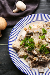 Plate with tasty cooked mushrooms on table