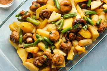 Baking dish with tasty cooked mushrooms and green beans on color background