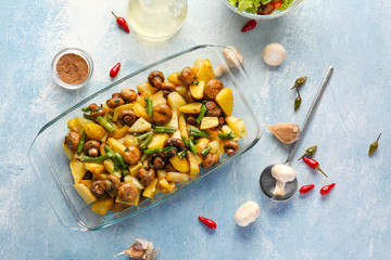 Baking dish with tasty cooked mushrooms and green beans on color background