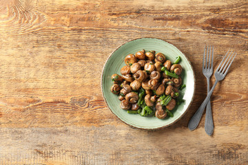 Plate with tasty cooked mushrooms and green beans on table
