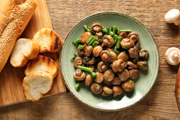 Plate with tasty cooked mushrooms and green beans on table