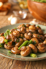 Plate with tasty cooked mushrooms and green beans on table, closeup