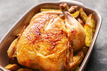 Dish with baked chicken and potato on dark background