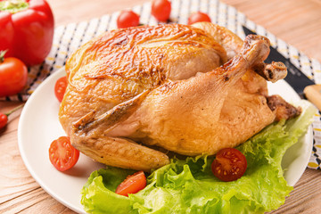 Plate with baked chicken on wooden table