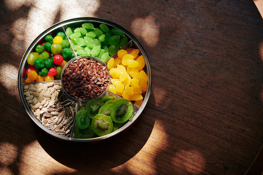 Round plate with seeds and dried sweet fruits on wooden table served for Tet celebration