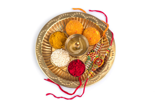 Indian Festival: Rakhi with rice grains, kumkum, sweets and diya on plate with an elegant Rakhi. A traditional Indian wrist band which is a symbol of love between Brothers and Sisters