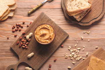 Bowl with tasty peanut butter and bread on table