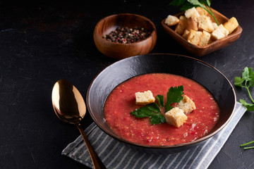 Homemade Spanish tomato soup Gazpacho with spice in black bowl on dark stone background