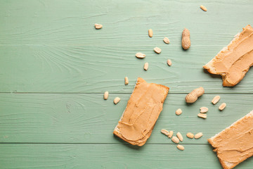 Slices of bread with tasty peanut butter on color wooden background