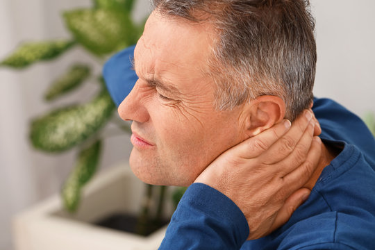 Mature man suffering from neck pain in bedroom - Powered by Adobe