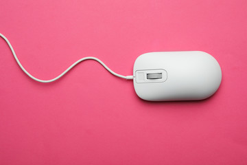 Wired computer mouse on pink background, top view