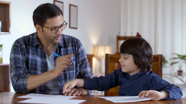 Father son duo spending quality time together in an Indian nuclear family . HD Video Clip of Indian parenting and father helping son with his homework. Indian father teaching his little son how to ...