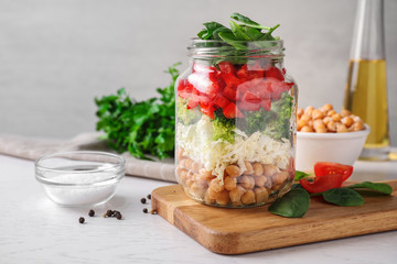 Healthy salad in glass jar on white table