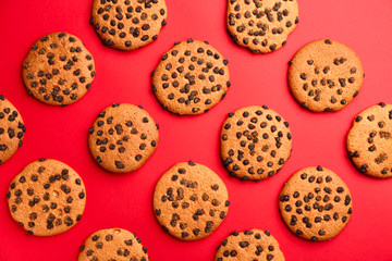 Tasty cookies with chocolate chips on color background