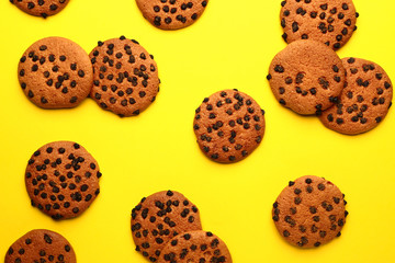 Tasty cookies with chocolate chips on color background